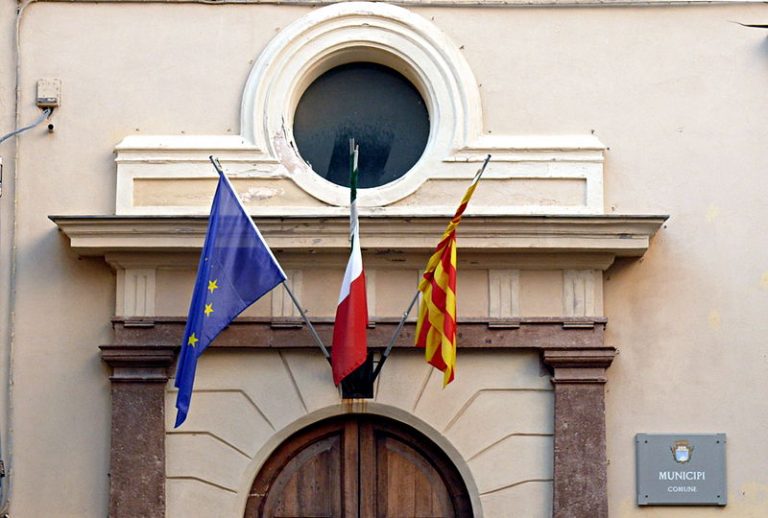 Actualment la senyera quadribarrada oneja a l'ajuntament alguerès juntament amb la bandera italiana i l'europea | Fotografia: Simone Zuffanelli