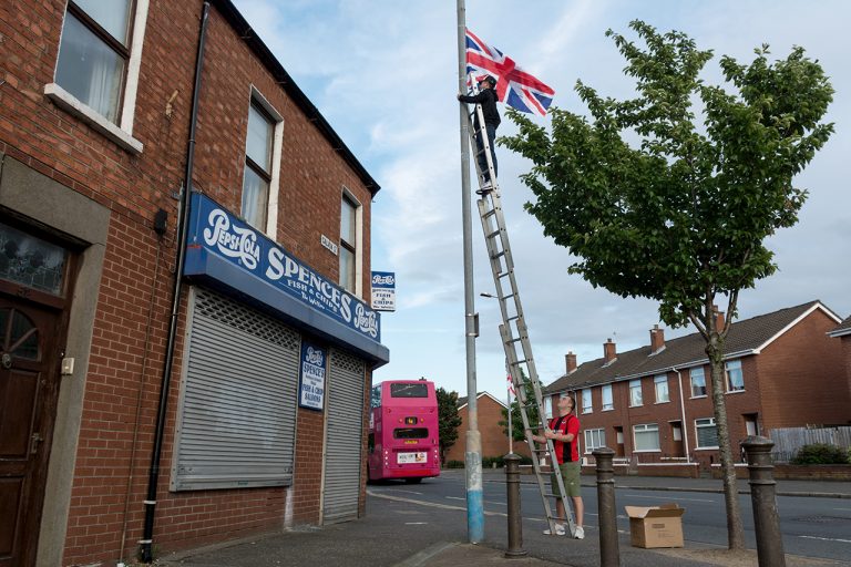 Dos homes pengen la bandera britànica a un barri unionista de l’est de Belfast. Les setmanes prèvies a la marxa Orange del 12 de juliol, es multiplica la simbologia nacional (i també la sectària). / Alfons Cabrera